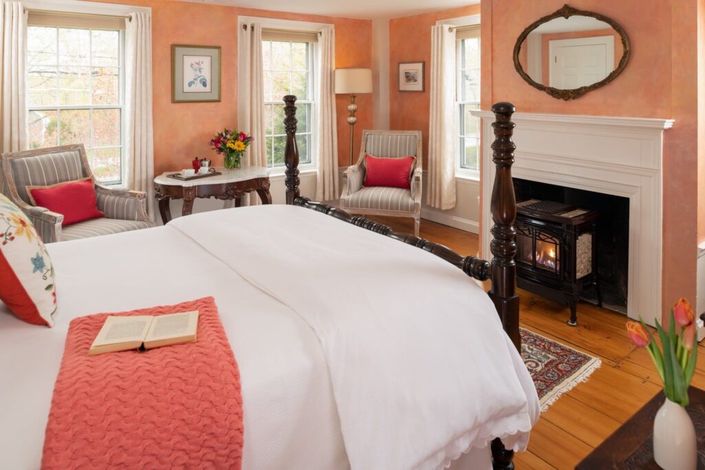 A second floor room at the Candleberry Inn with a Queen-sized bed and gas fireplace, comfortable chairs.