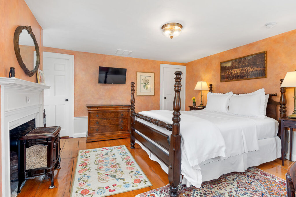 A second floor room at the Candleberry Inn with a Queen-sized bed and gas fireplace, comfortable chairs.