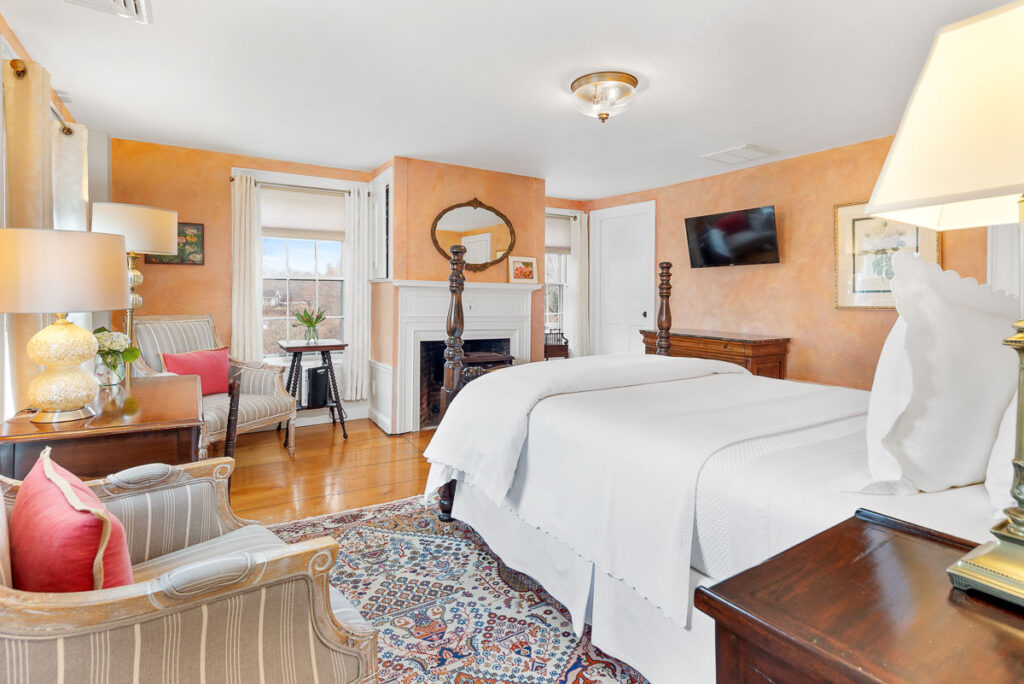 A second floor room at the Candleberry Inn with a Queen-sized bed and gas fireplace, comfortable chairs.